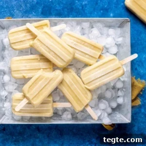 Creamy Homemade Banana Popsicles Recipe for Cooling Summer Treats 12 banana popsicles laid flat in an aluminum tray.