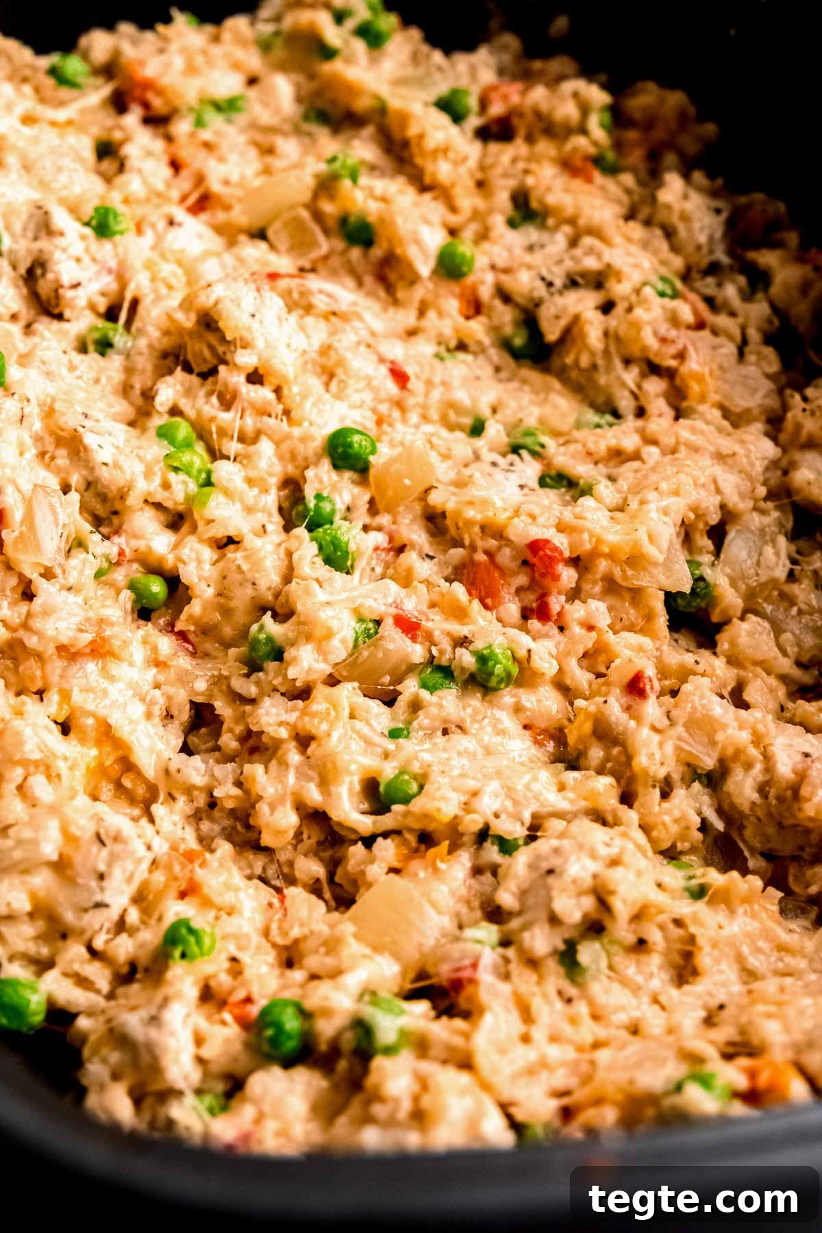 crockpot filled with cheesy chicken and rice with peas and carrots