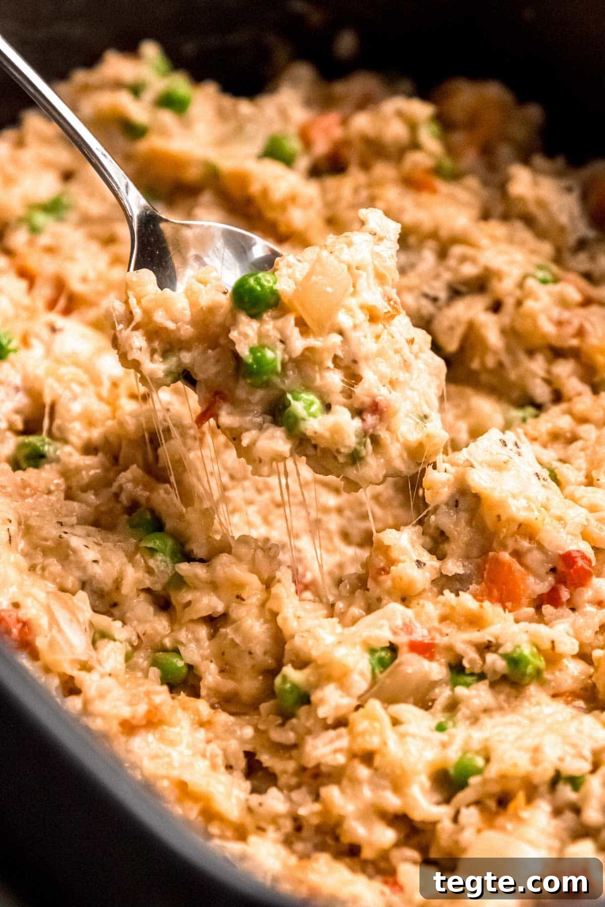 a cheesy bite of chicken and rice in a crockpot with peas and carrots