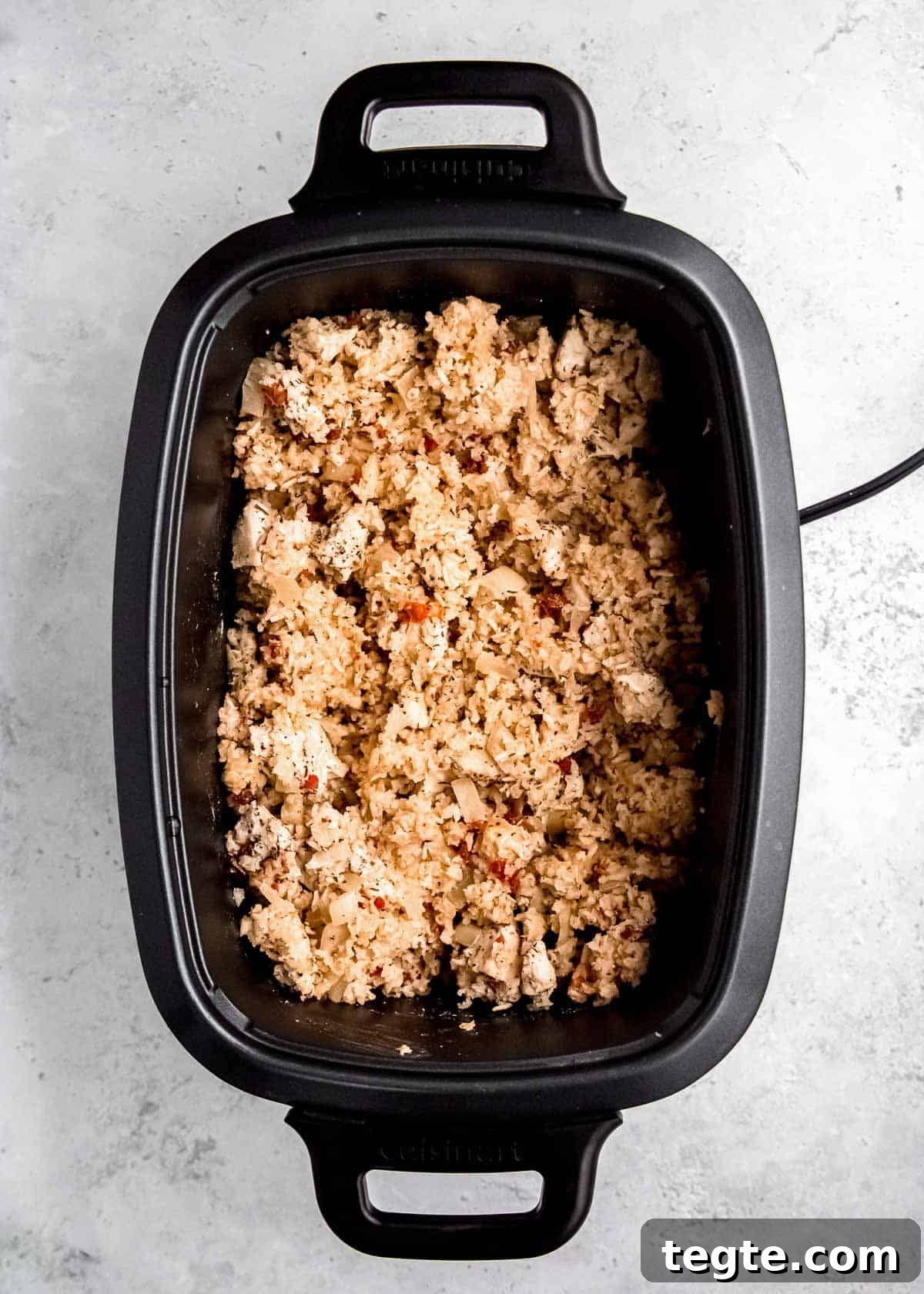 Cooked chicken and rice in a slow cooker with pimentos and onions