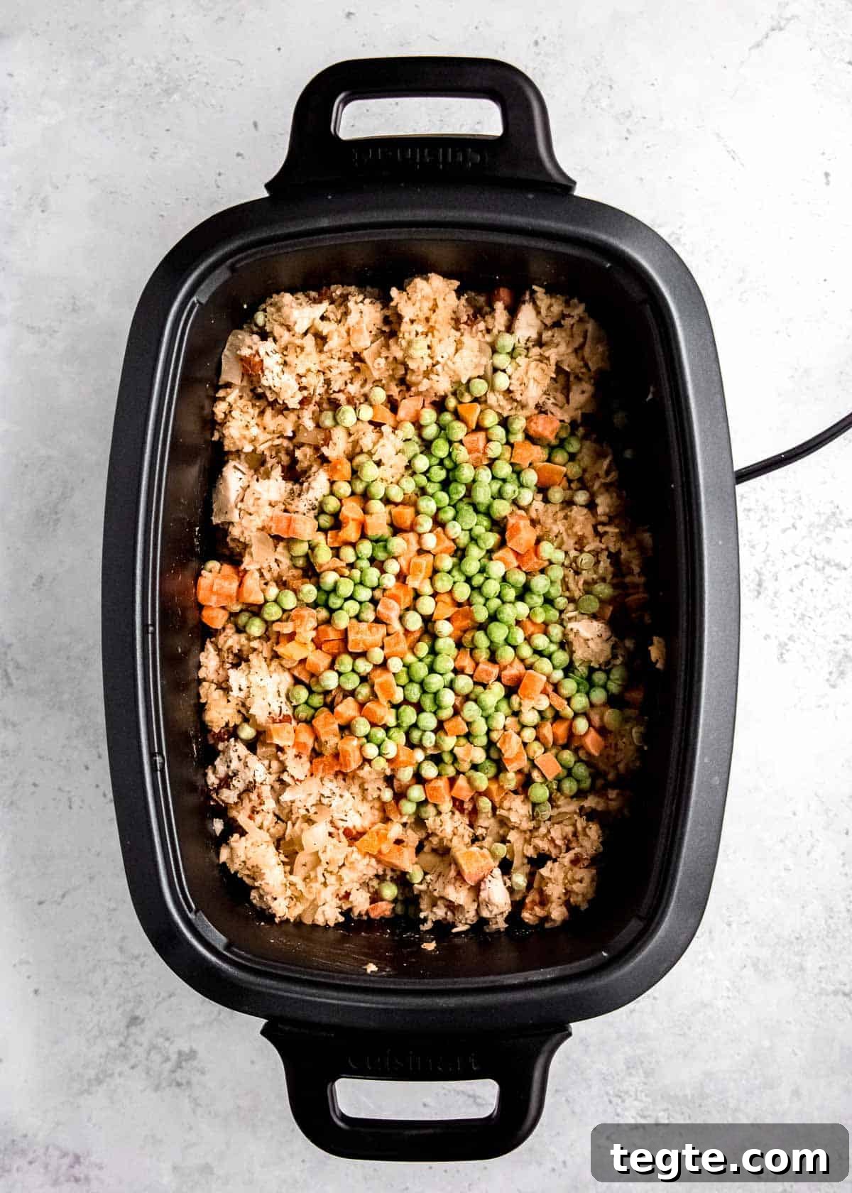 peas and carrots added to a crockpot full of chicken and rice