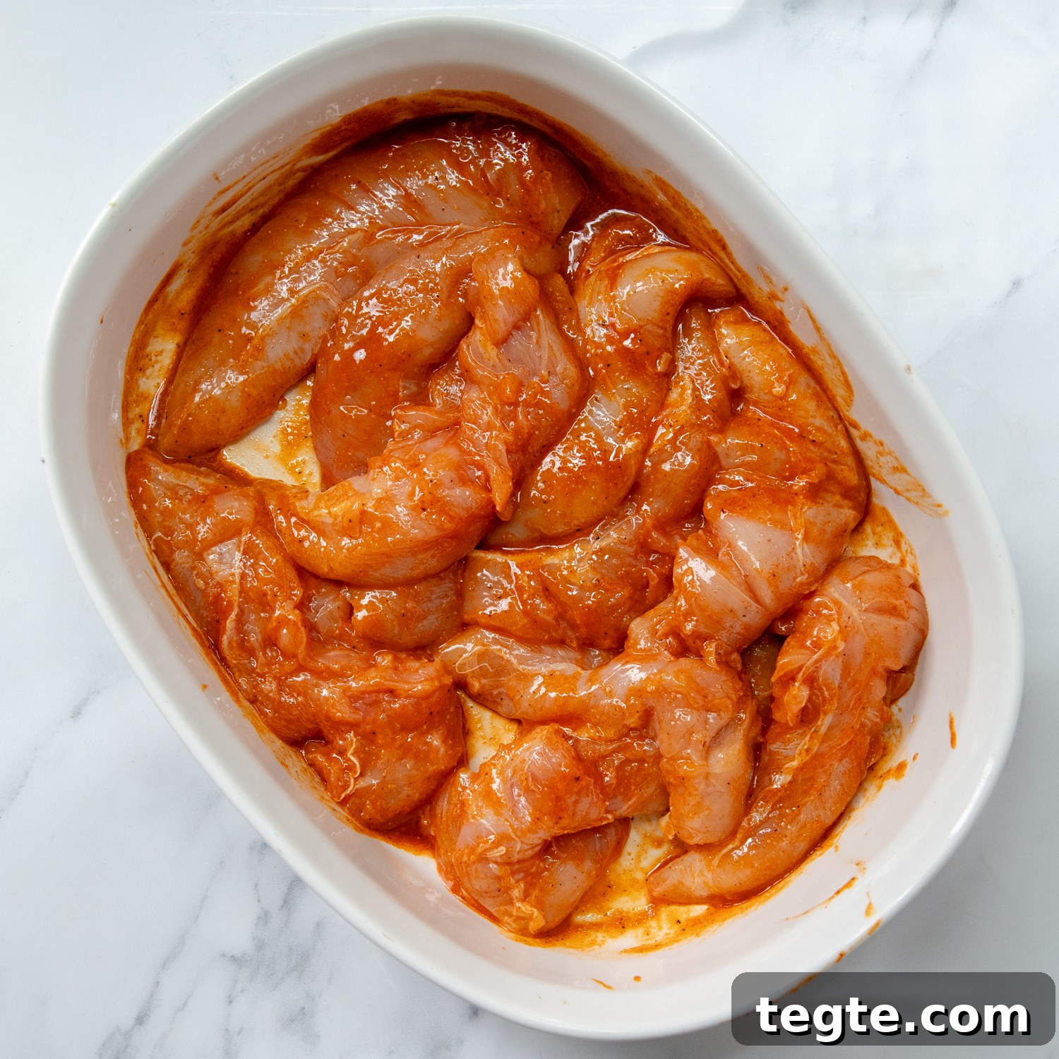 Grilled Buffalo Chicken Tacos with Tangy Slaw and Marinade 3 chicken marinating in a large oval white bowl.