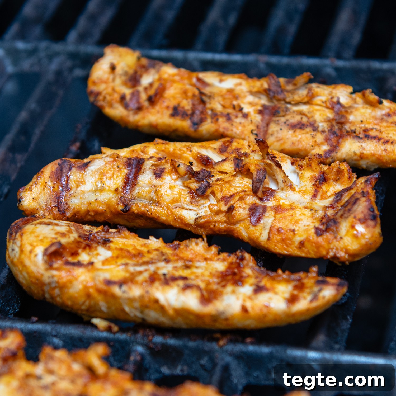 Grilled Buffalo Chicken Tacos with Tangy Slaw and Marinade 5 chicken tenderloins cooking on a grill with grill marks.