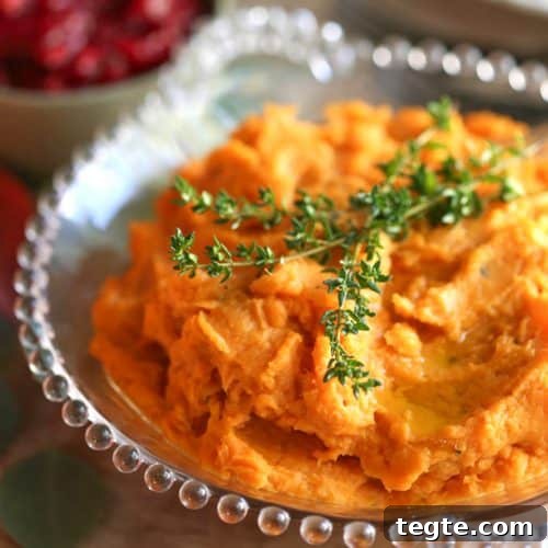 savory mashed sweet potatoes with fresh thyme on top in a glass bowl.