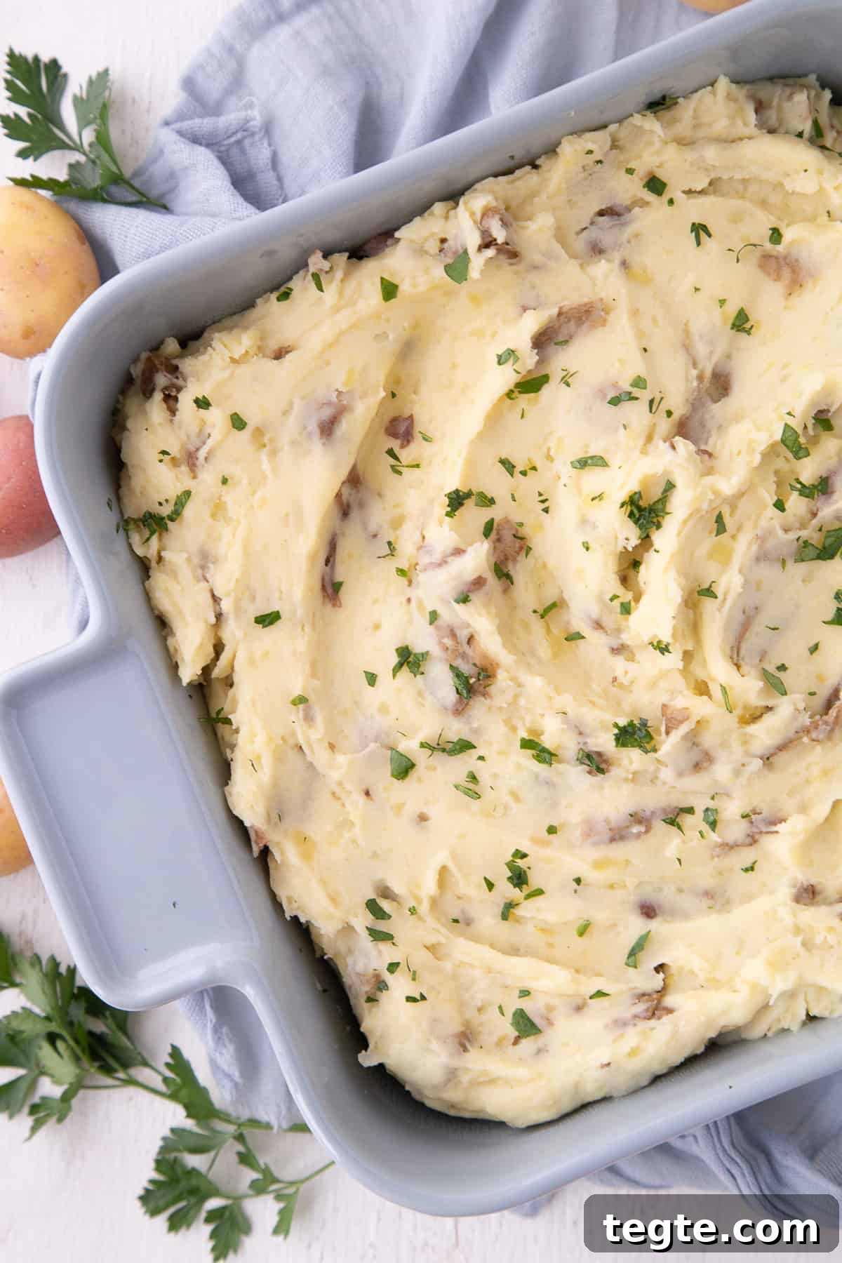Creamy Mashed Potato Casserole Without Peeling Potatoes 9 mashed potato casserole in a blue dish on a blue tea towel