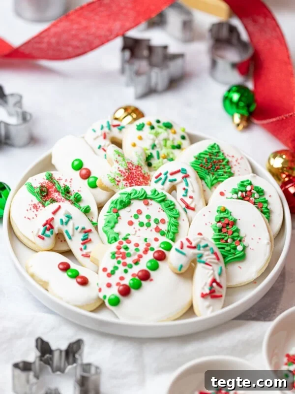 Authentic Japanese Strawberry Shortcake Recipe — Fluffy, Light Slice 17 Christmas cut out cookies on a plate with sprinkles and royal icing decoration next to cookie cutters, ornaments, and red ribbon