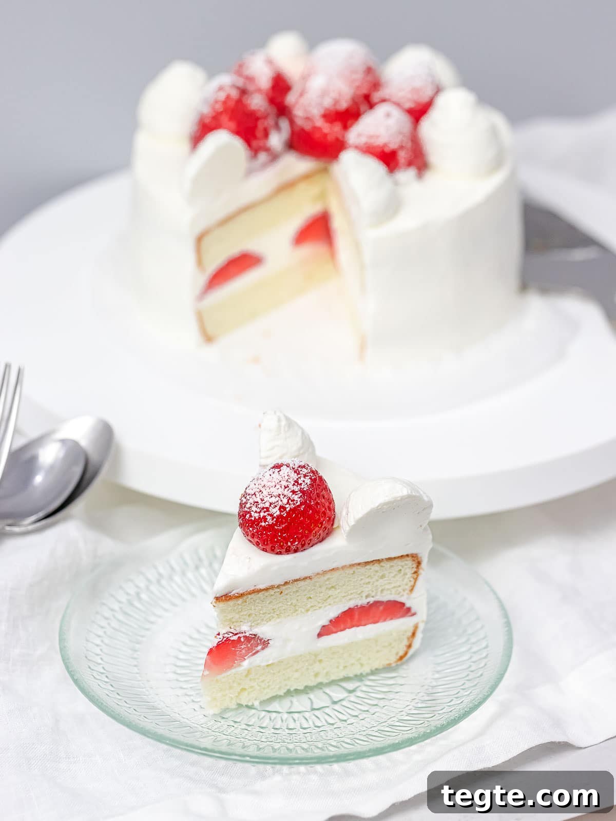 Authentic Japanese Strawberry Shortcake Recipe — Fluffy, Light Slice 10 a slice of Japanese strawberry shortcake on a glass plate with the whole cake in the background