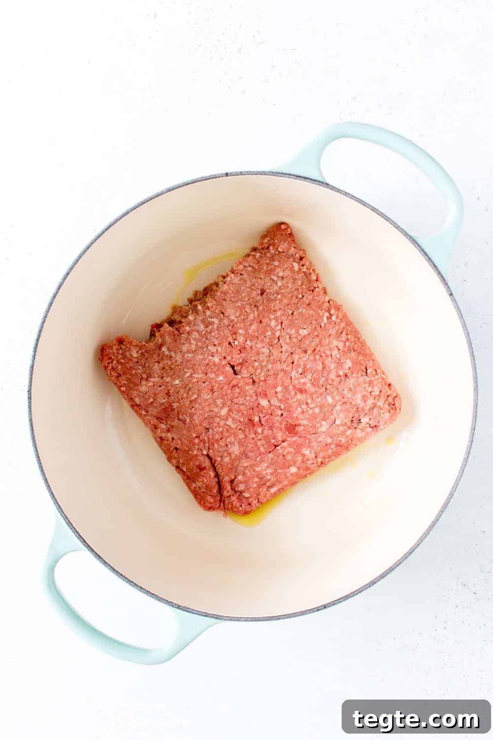 Ground beef added to a pot.