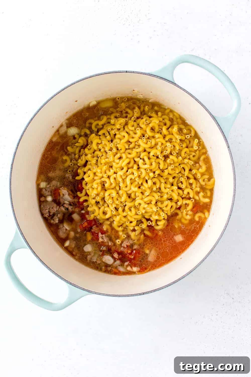 Pasta added to a pot with beef, salsa, and broth.
