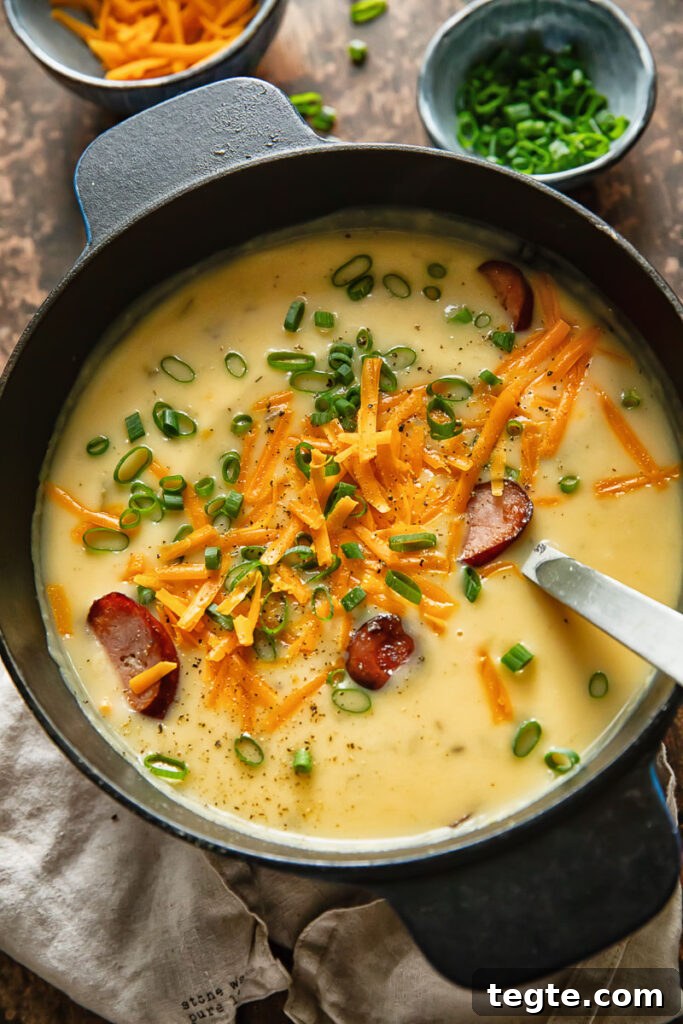Hearty Kielbasa and Potato Soup Recipe 4 Top down shot of kielbasa potato soup in a pot topped with green onions and grated cheese