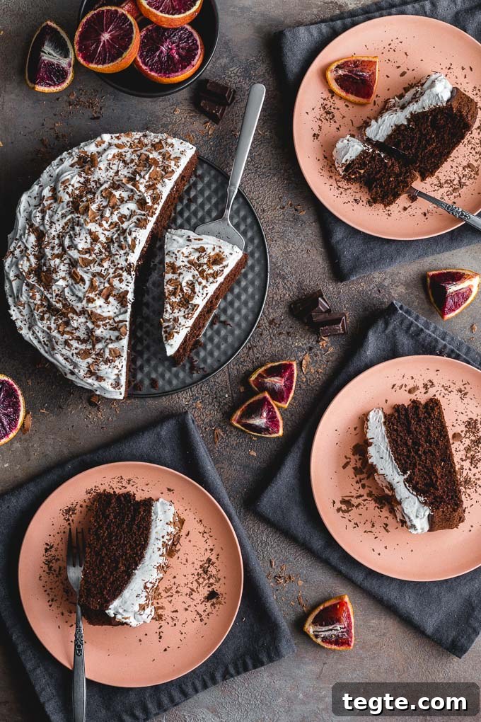Dairy-Free Blood Orange Chocolate Cake Recipe 2 Overhead view of a frosted chocolate cake with slices being served onto pink plates.