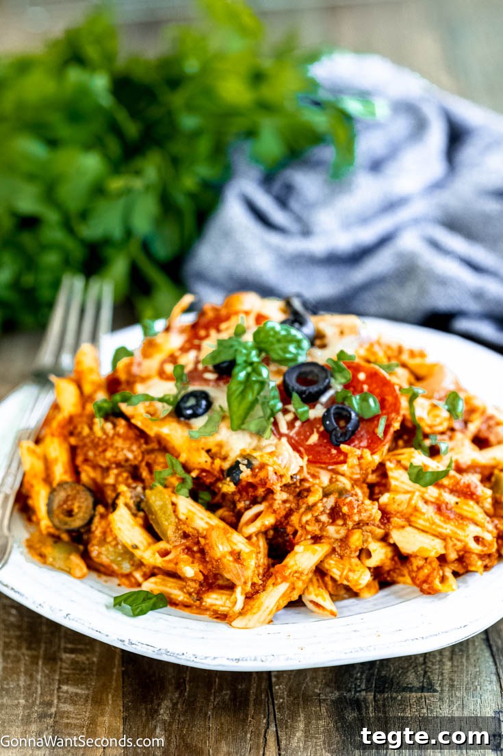 Our deliciously hearty pizza casserole will be kids of all ages will race to the dinner table when this is on the menu! Ooey-gooey, cheese YUM! #pizzacasserole #pizzapastacasserole pizza casserole on a plate