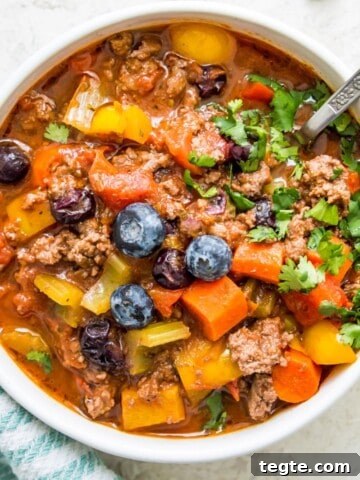 A bowl of no bean chili topped with fresh blueberries and chopped cilantro.