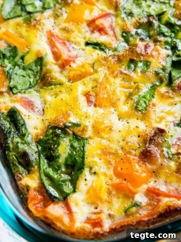 A glass dish filled with a bacon and vegetable egg casserole.