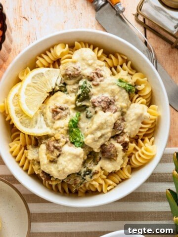 A bowl of spinach and artichoke casserole over noodles.