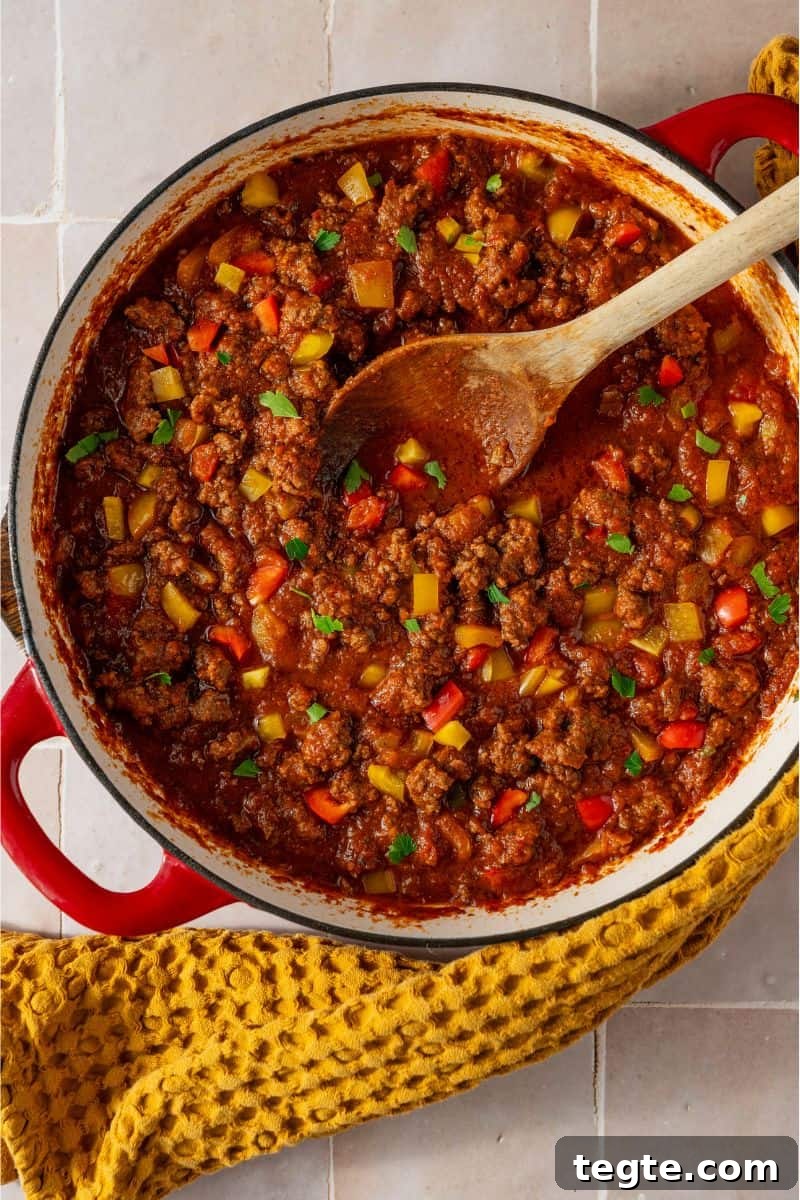 Lean Ground Beef Sloppy Joes with Tangy Tomato Sauce 9 A pan with a tomato sauce and ground beef mixture in it with a spoon in the sauce.