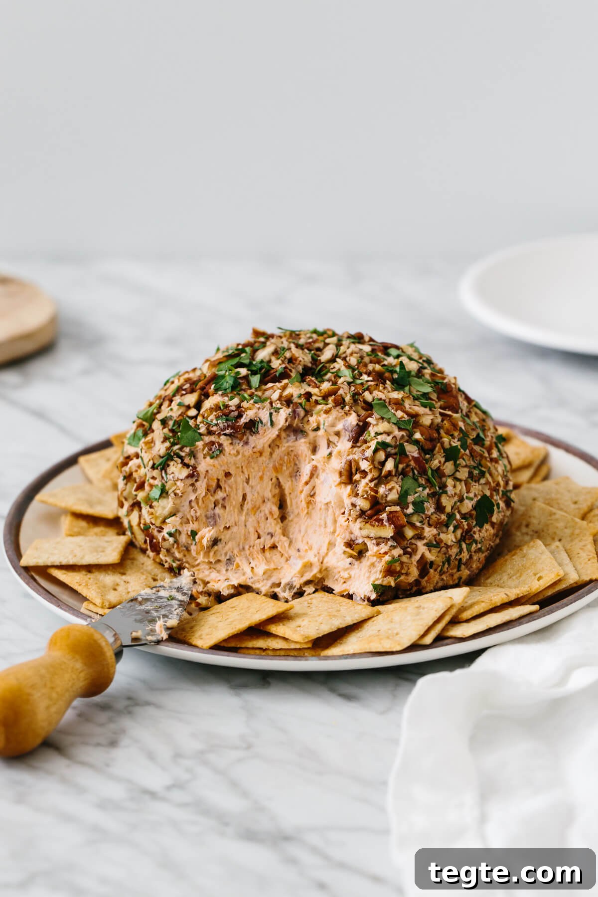 13 Festive Christmas Appetizers Your Guests Will Love 11 Salmon cheese ball on a plate surrounded by crackers.