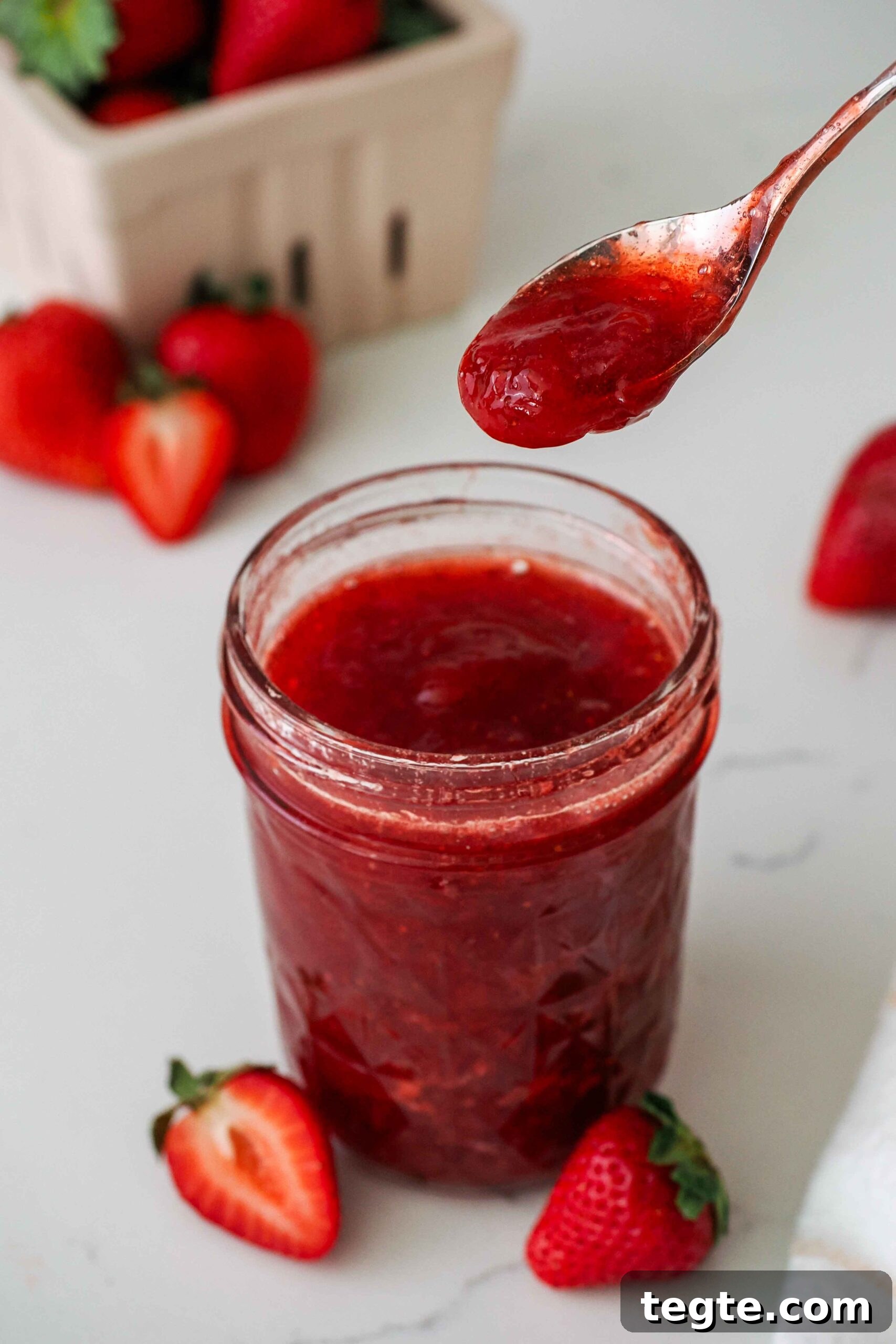 Homemade Small-Batch Strawberry Jam Recipe for Fresh Preserves 2 A spoon with strawberry jam over an open jar of jam.