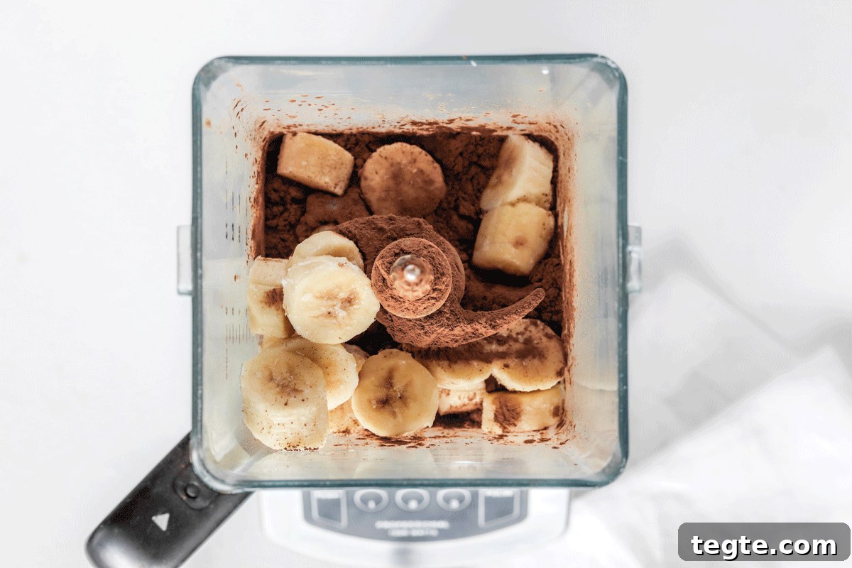 Chunks of bananas, cocoa powder and milk in a blender