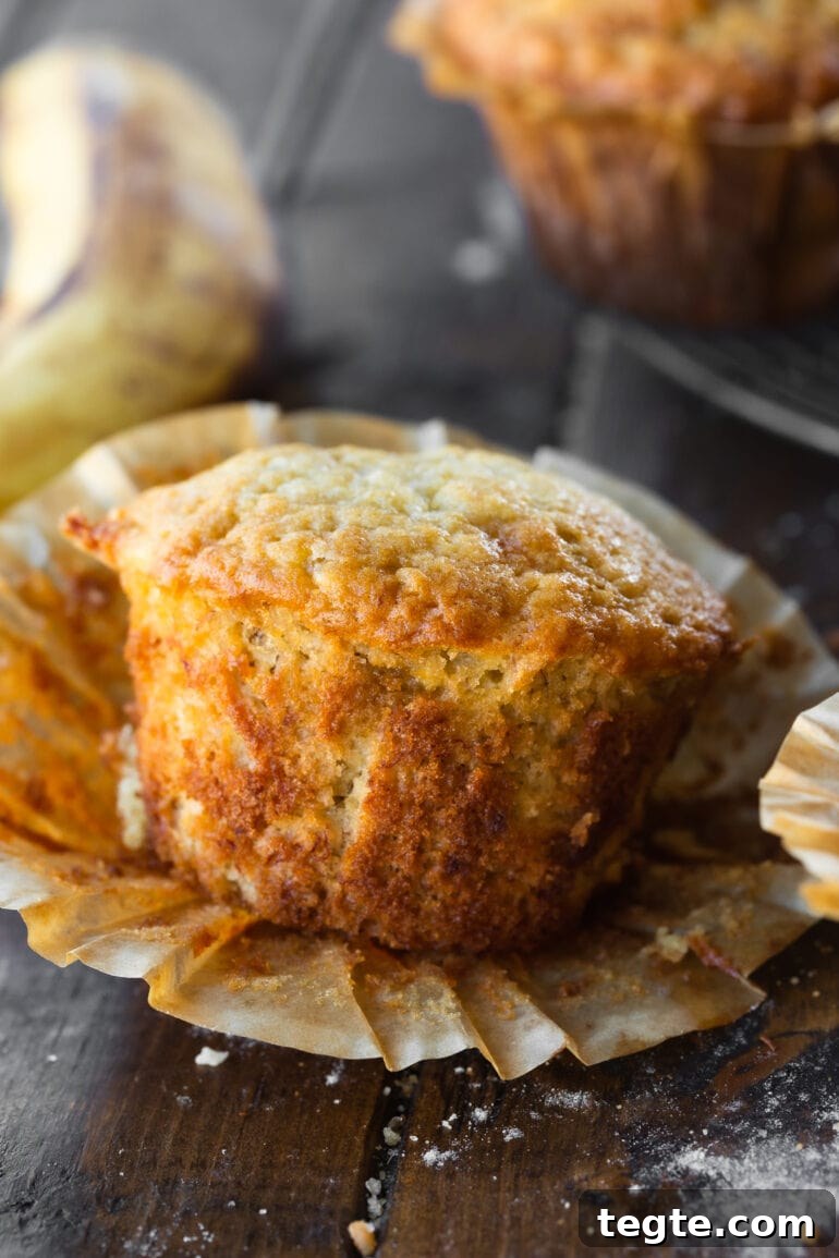 One-Bowl Banana Muffins with Moist, Quick Preparation 3 a photo of a baked banana muffin with the wrapper peeled off so you can see the side of the muffin