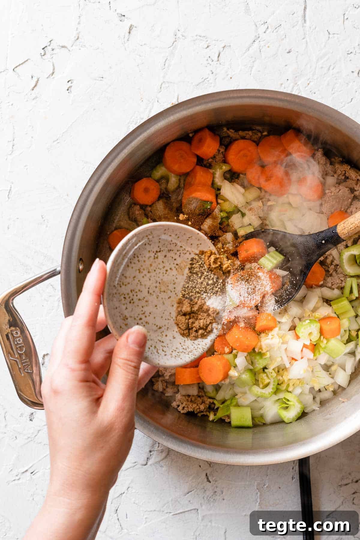 small dish of seasonings being poured into soup pot