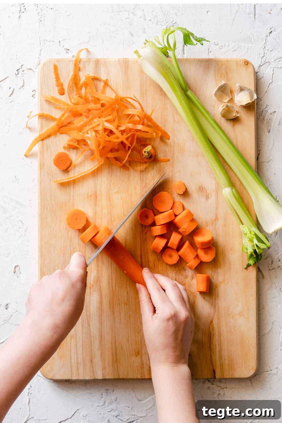 carrots being sliced on wooden cutting board