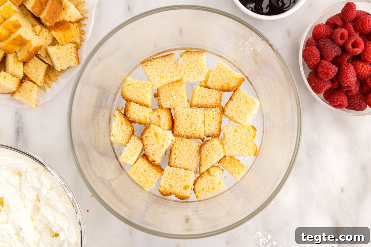 Decadent Raspberry Trifle Recipe with Fresh Cream and Cake 11 pound cake cubes on the bottom of a trifle bowl