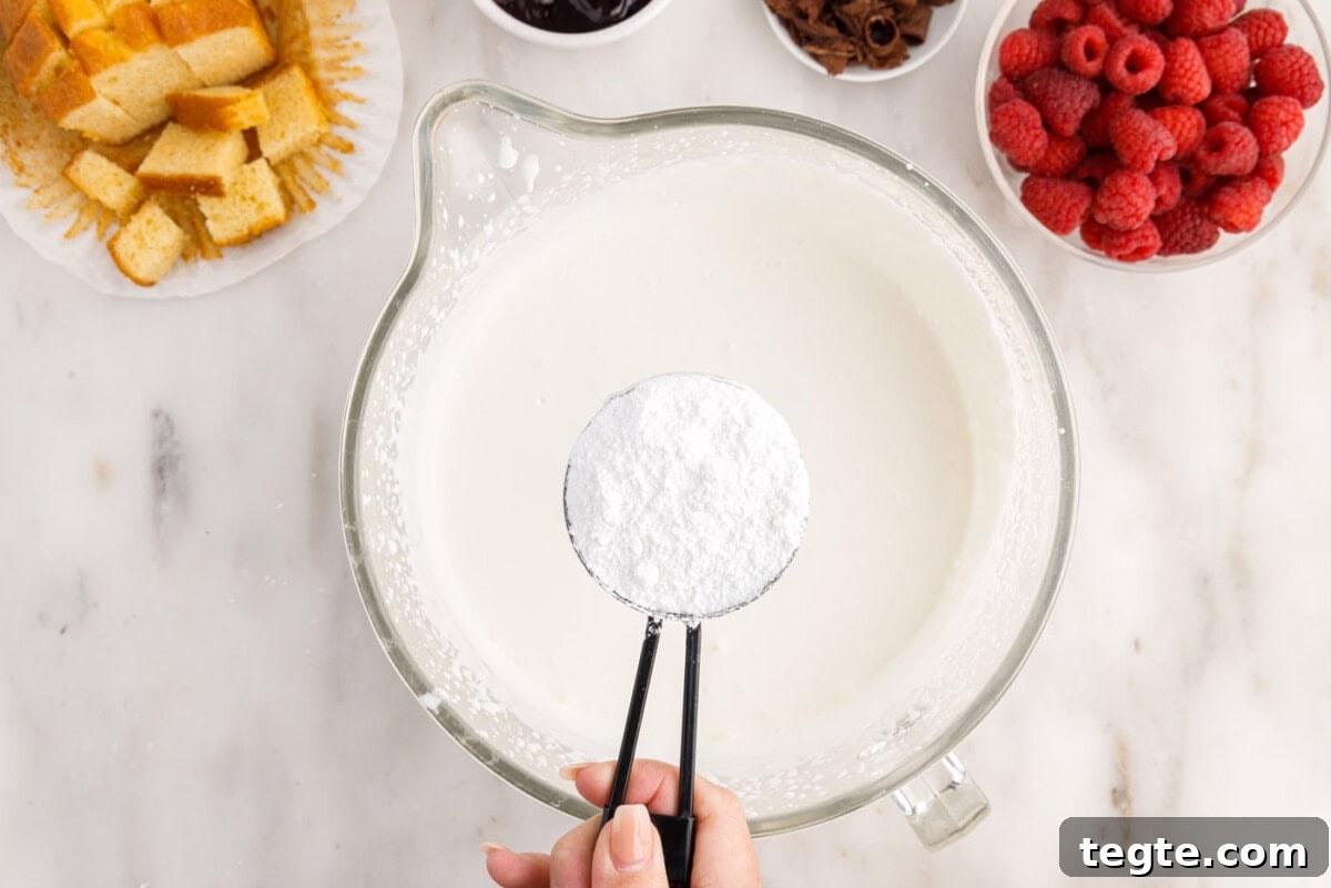 Decadent Raspberry Trifle Recipe with Fresh Cream and Cake 7 adding powdered sugar to heavy whipping cream in a bowl