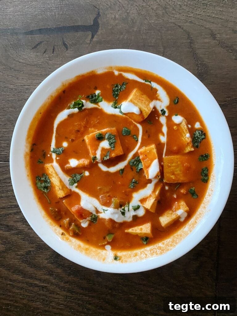 paneer makhani in a bowl on a hardwood floor backdrop