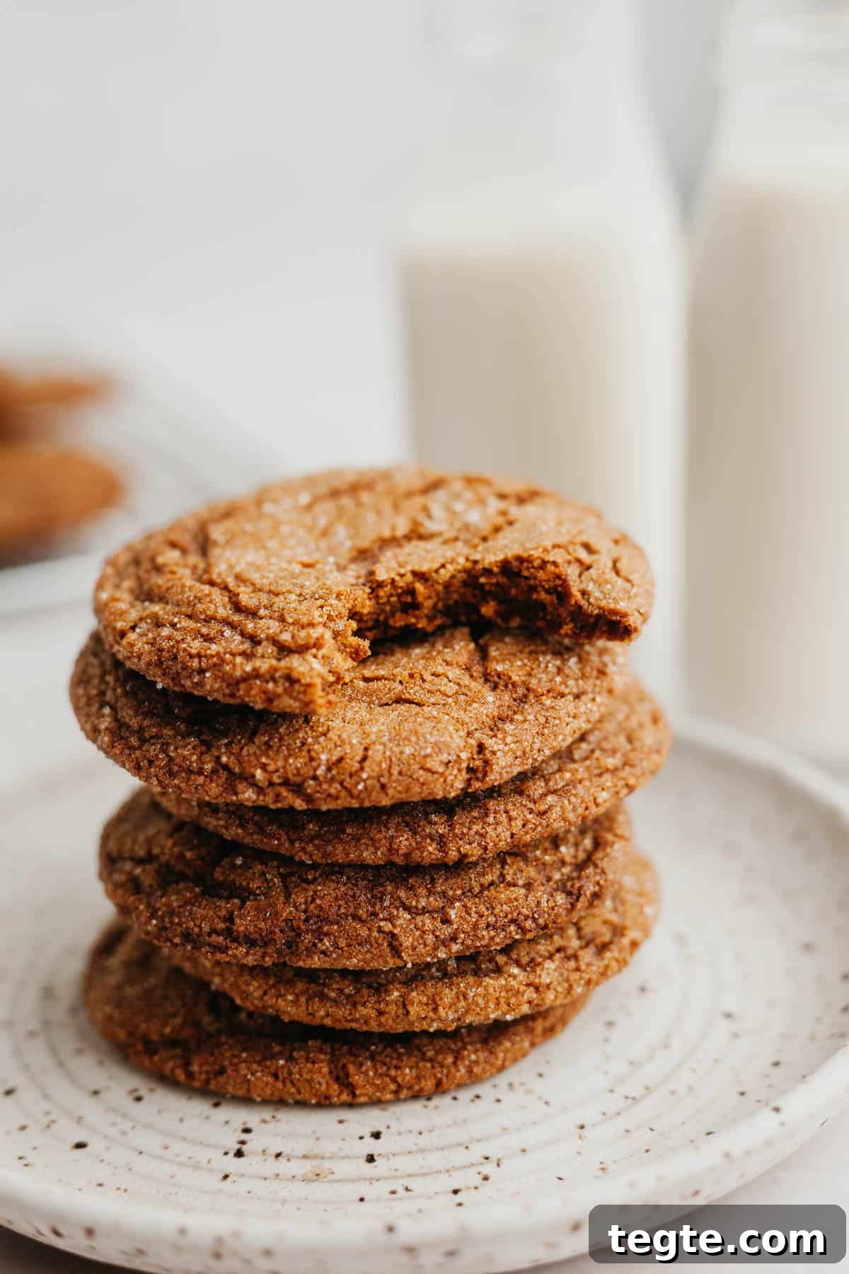 A stack of molasses cookies, the cookie on top has a bite taken out of it.