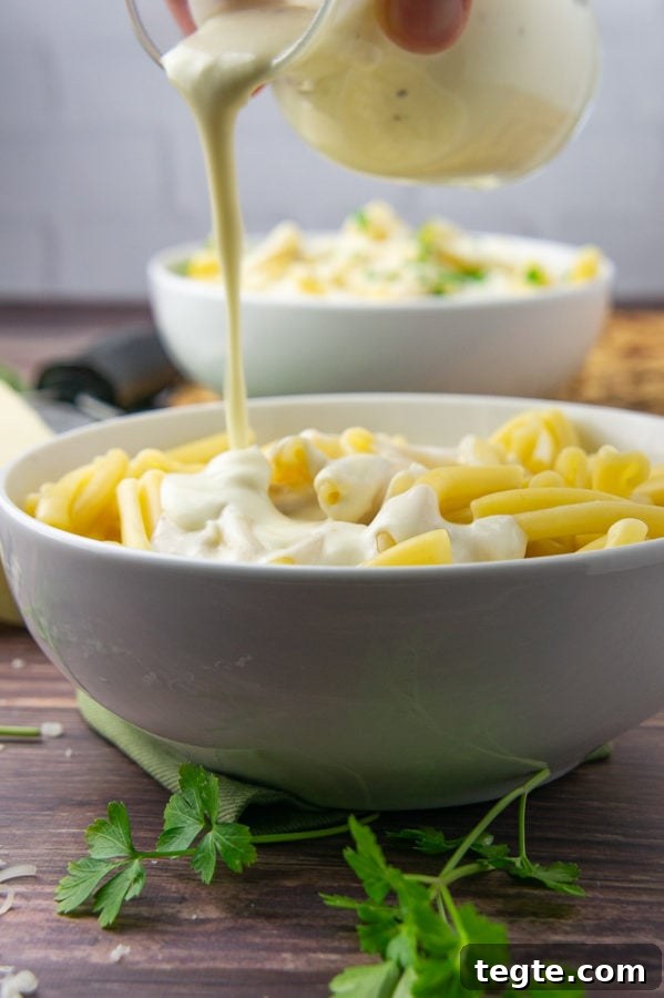 Creamy Asiago Sauce for Pasta and Vegetables 5 a bowl of pasta with asiago sauce being poured over top