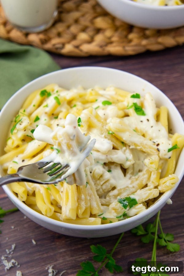 Creamy Asiago Sauce for Pasta and Vegetables 6 A fork with creamy sauced noodles on it over a bowl of pasta