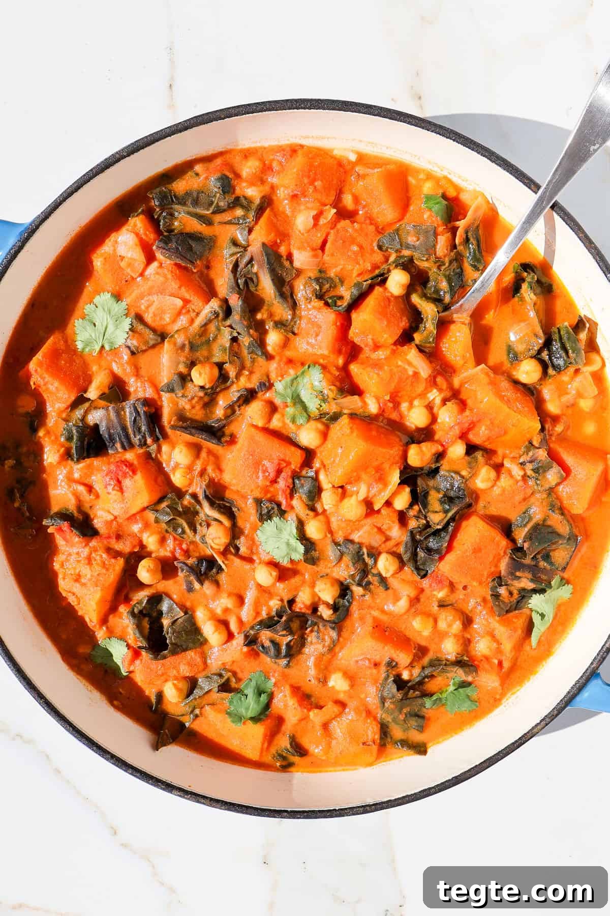 Butternut Squash and Chickpea Curry Recipe for Cozy Dinners 10 Butternut squash curry in a pot with a spoon.