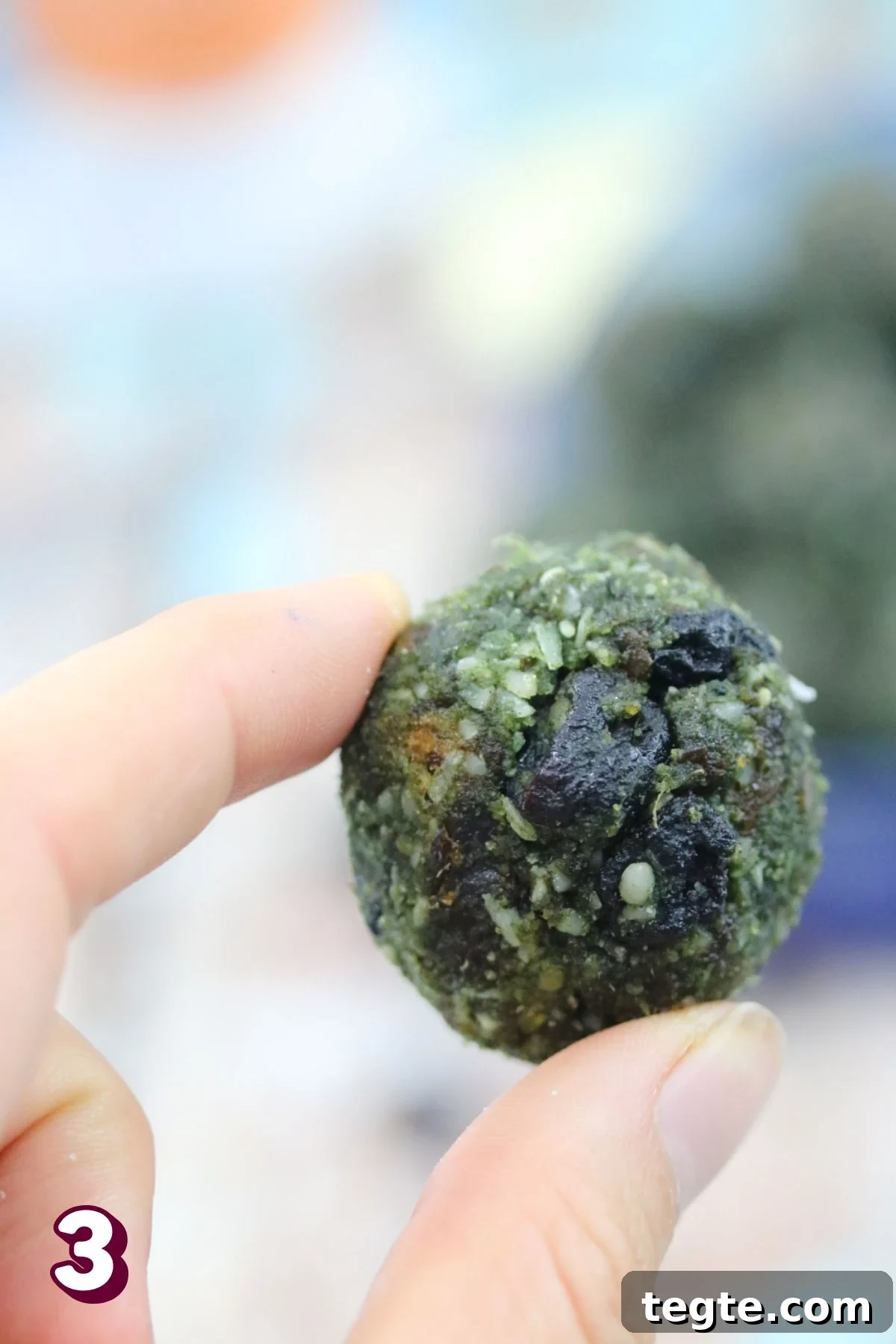 Energizing Spirulina Protein Balls (Gluten-Free) 6 Two fingers holding up a spirulina energy ball.