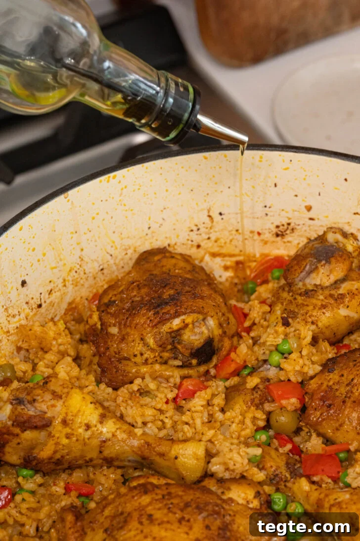 Authentic Puerto Rican Arroz con Pollo Recipe: Traditional Flavor Guide 11 Oil drizzling over a pot of arroz con pollo.