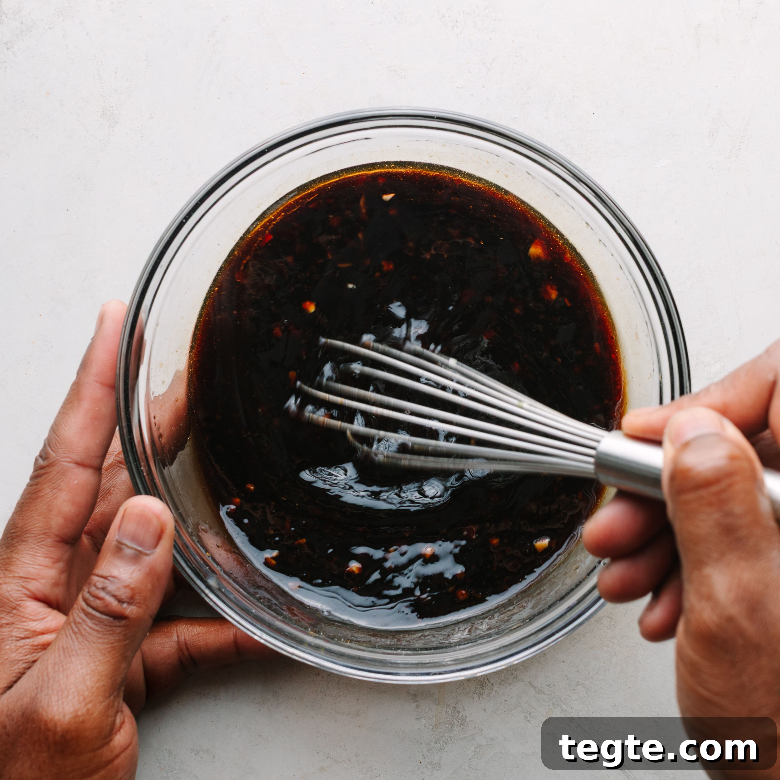 Asian Chili Garlic Chicken Wings Recipe 12 African American hands stirring Asian wing sauce.