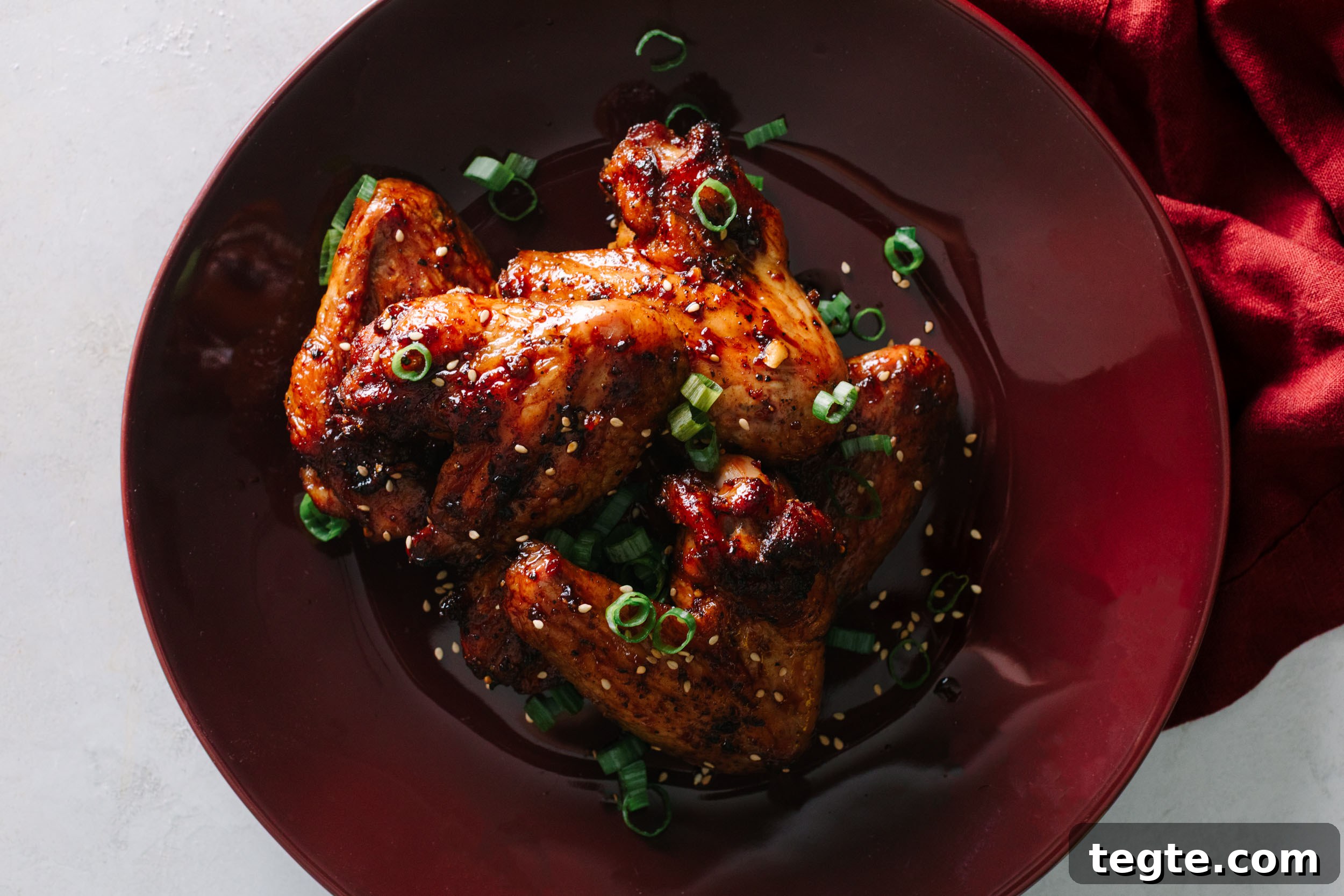 Asian Chili Garlic Chicken Wings Recipe 17 Asian chicken wings garnished with sesame seeds and green onions on a plate.