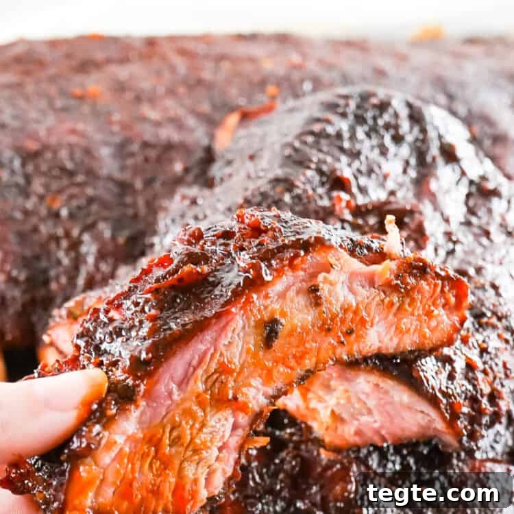 Hand holding a piece of smoked ribs